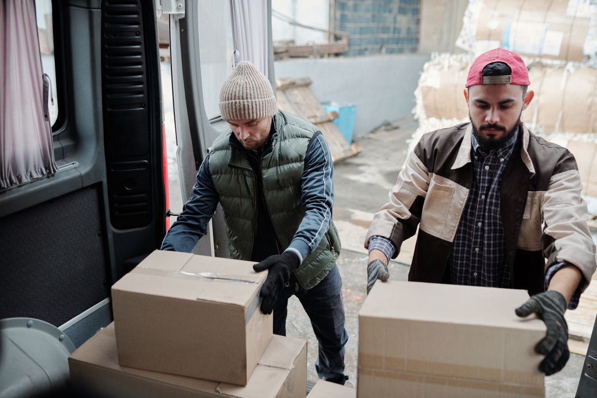 Two workers loading boxes into a van